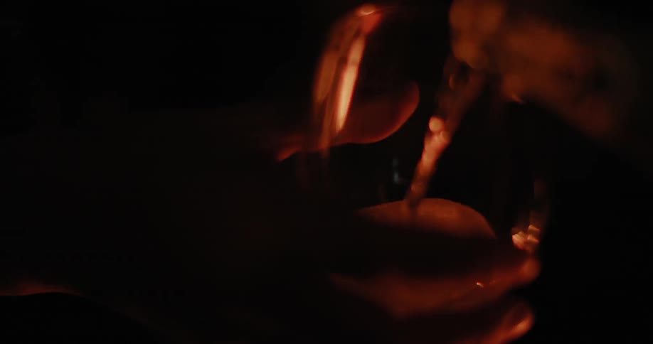 A drink is poured near a fire at night