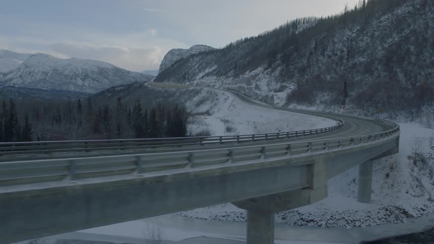 Reveal of a car driving on a bridge over snow covered ground