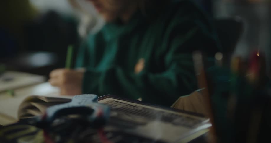 Blonde girl wearing a green hoodie writes in a notebook