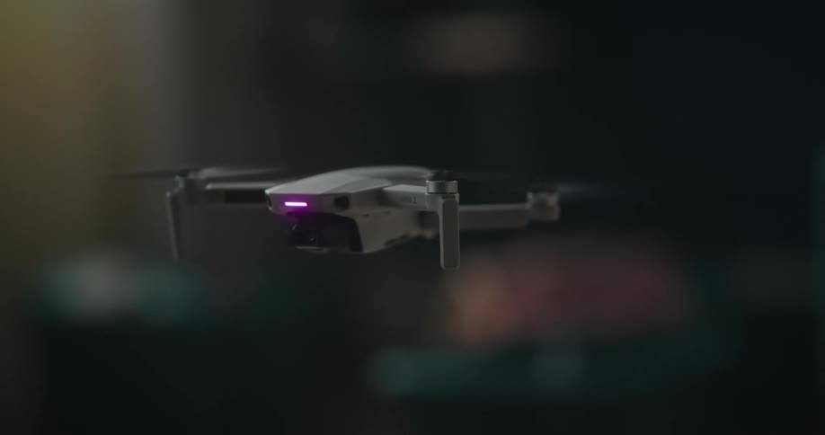 A small white drone takes off from the floor of a house