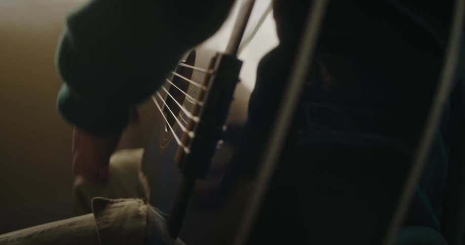 A person playing the guitar in a poorly lit place