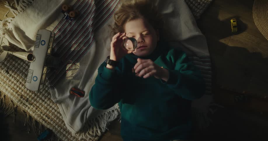 A child lying in bed with a transparent sphere in his hand