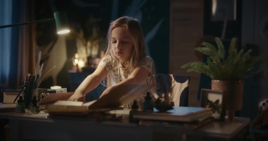 Girl at a table at home picking up some papers