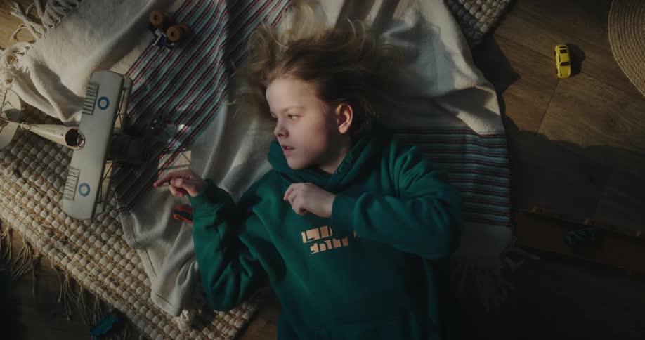 A young girls spins the propeller on a toy airplane while she lays on her back