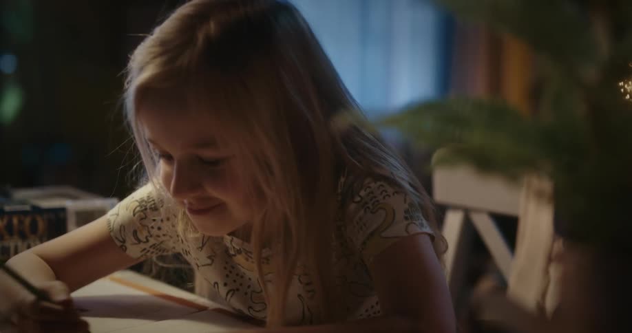Blonde girl sitting at table writes in a notebook smiling