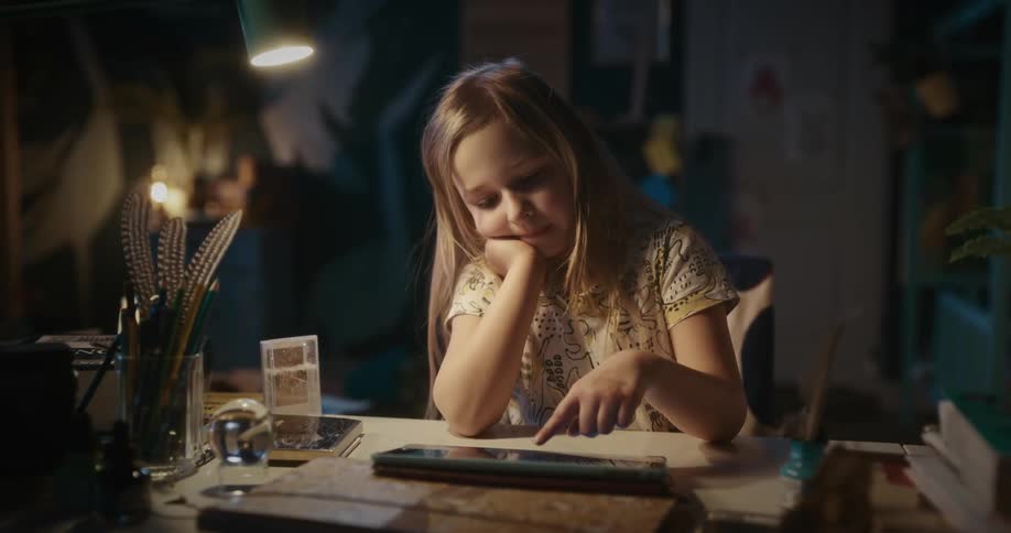 A cute little girl typing on a tablet