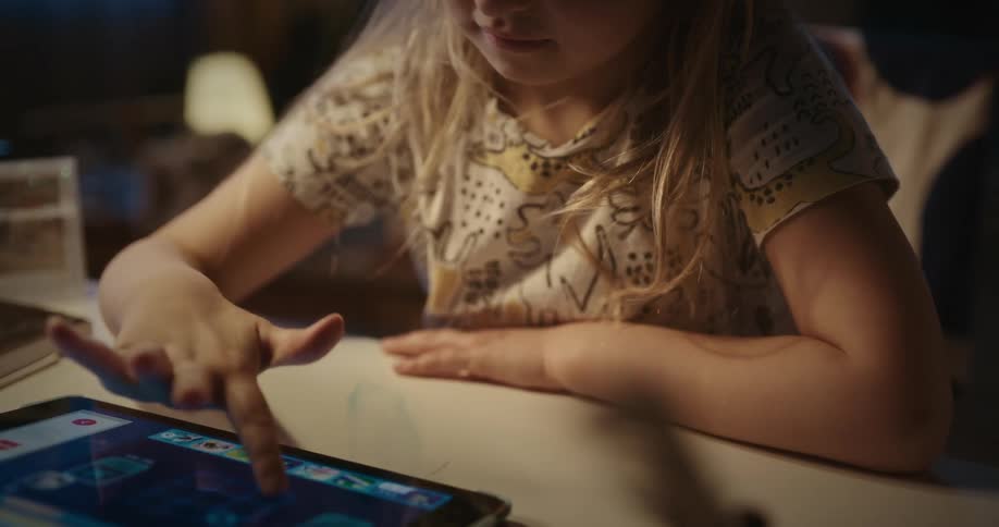 Girl plays with tablet while sitting at home at night