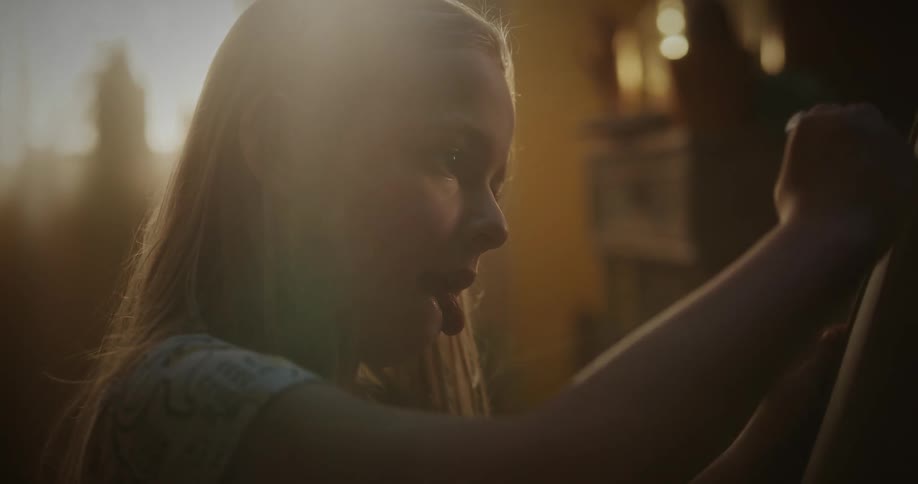 A blonde girl drawing on a blackboard as the sun shines through the window