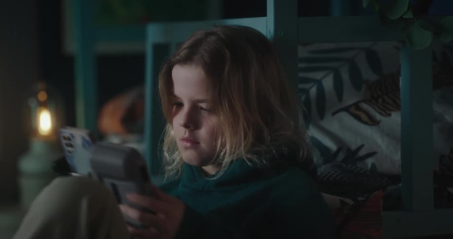 Blonde girl with a green hoodie uses a flight controller in her room sitting on the floor