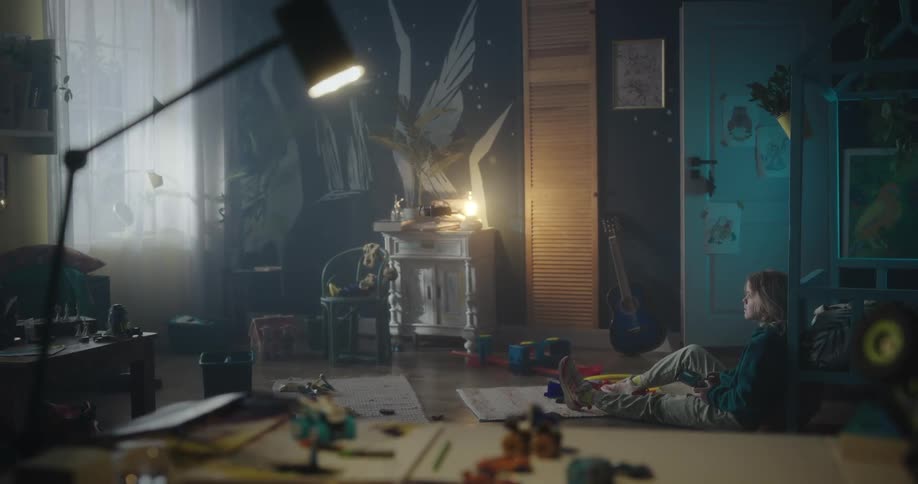 A blonde girl sitting on the ground controls a drone in her room