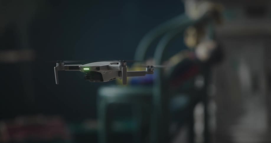 A small drone rotates as it flies in the air and lands on the floor