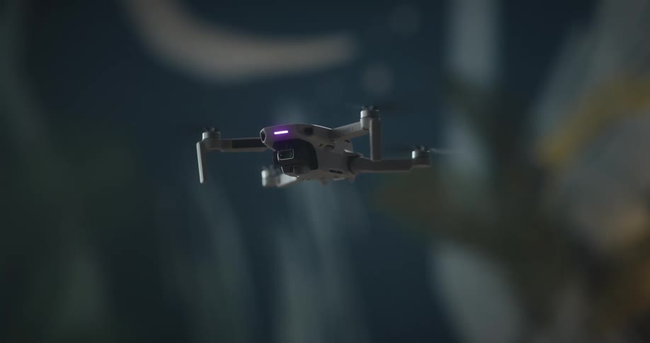 Lights flash on a small drone as it flies and turns