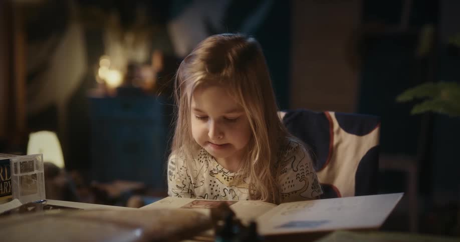 A blonde girl reads a book and turns a page