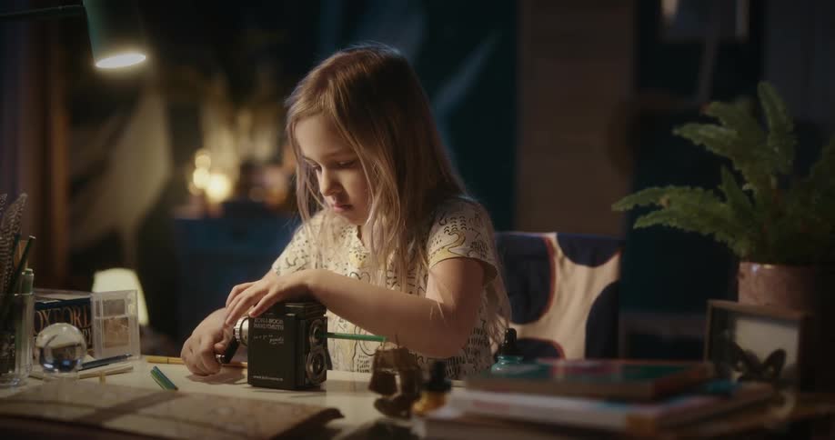Little blonde girl placing a straw into a small manual machine