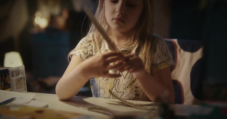 A little girl at a table playing with feathers