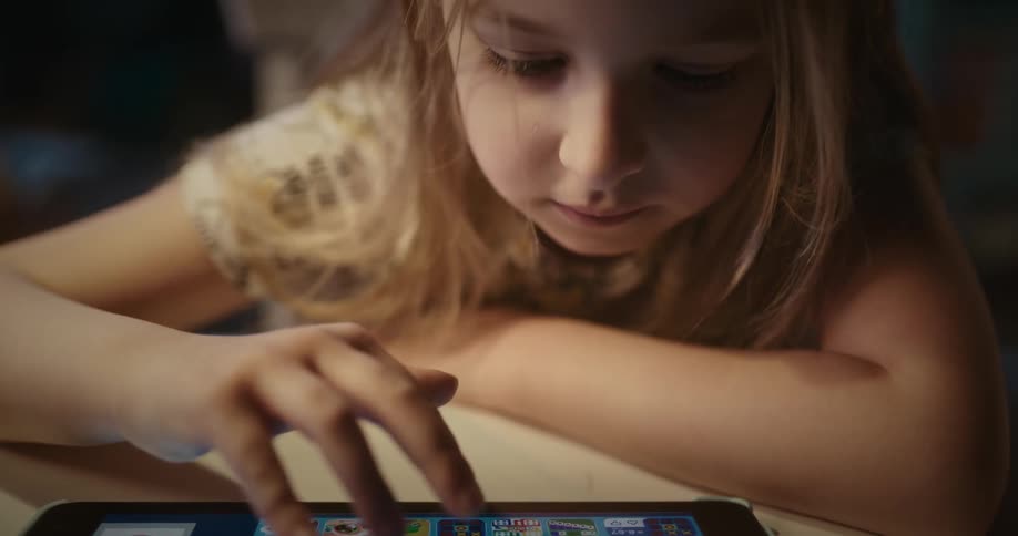 Blonde girl uses tablet smiling in her room