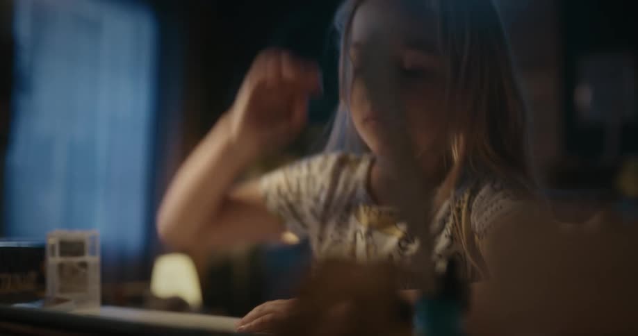 Bored blonde girl uses tablet sitting at table