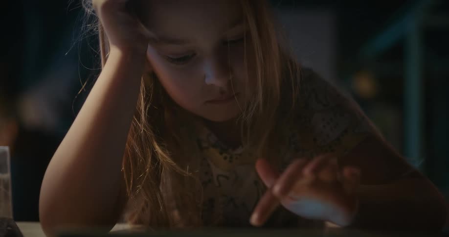 Blonde girl plays with tablet at home