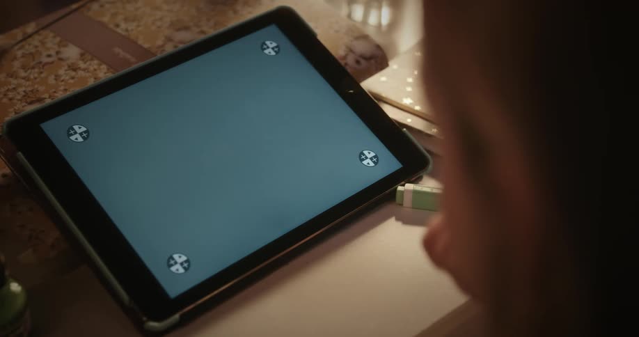 A person pressing their finger on a tablet screen that is blue