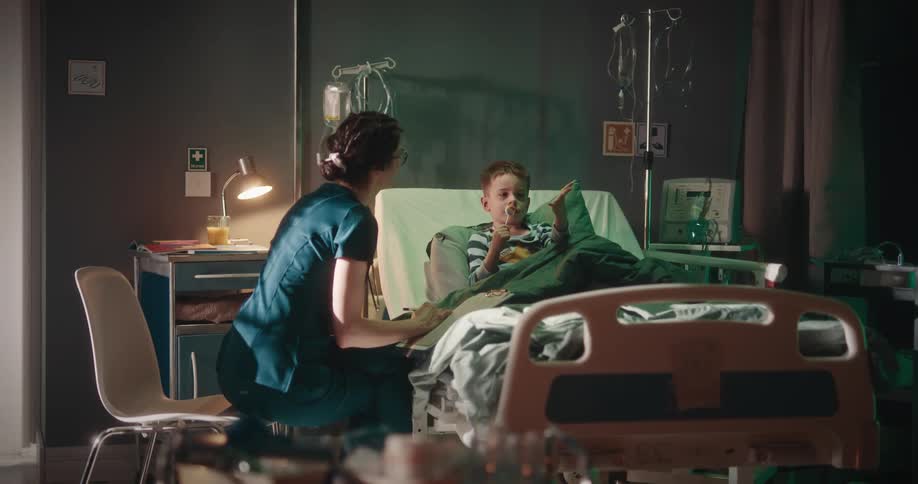 A doctor talks to a fidgety boy on a hospital bed
