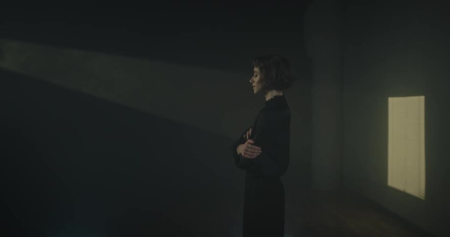Woman with crossed arms inside a room with a reflection of light passing on her face