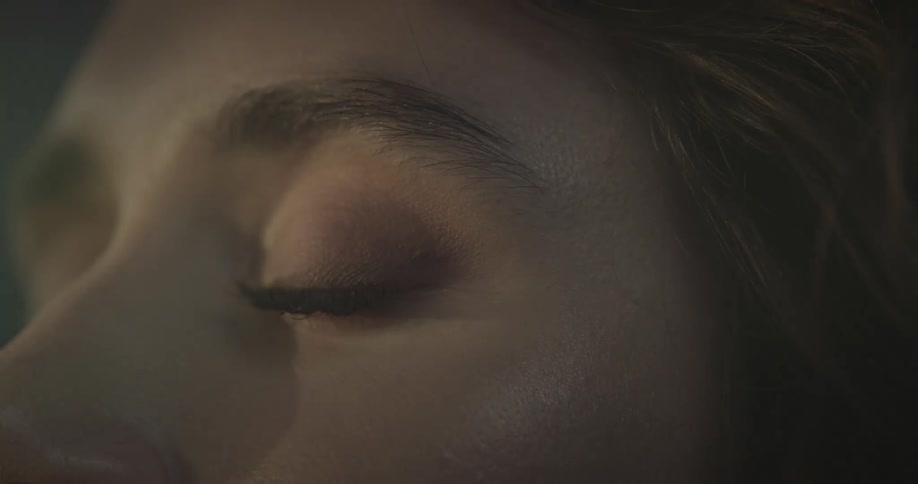 A closeup of a woman with closed eyes and brown hair