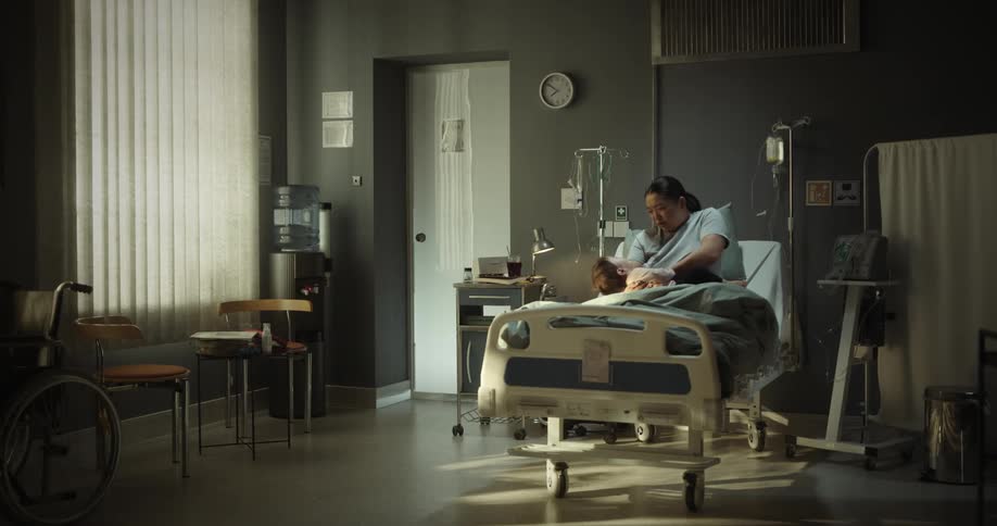 A woman in a hospital bed is breastfeeding her baby