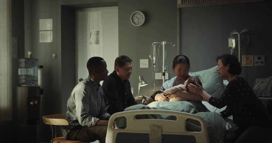 A woman in a hospital bed with a baby on her lap