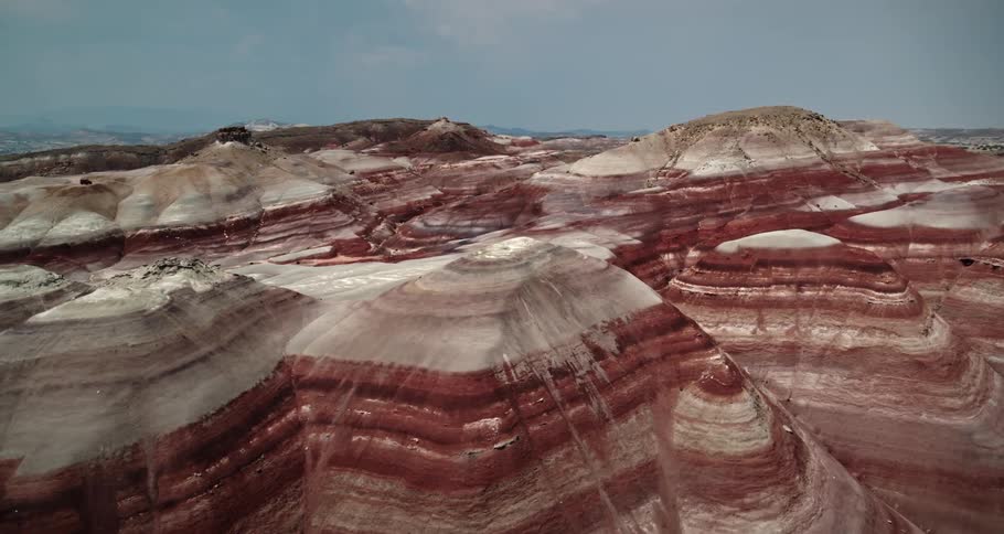 Rock layered mountains stretch across the desert with mountains in the distance