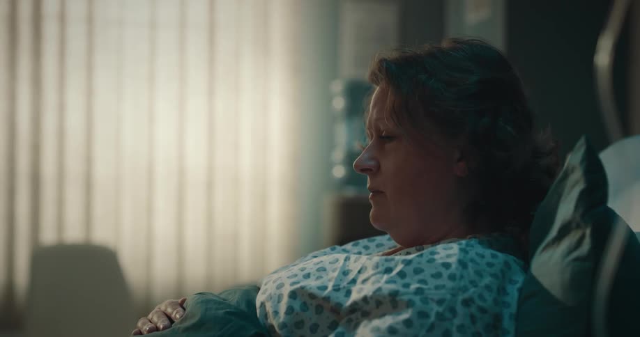 A woman is lying in a hospital bed and is thinking