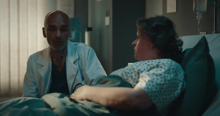 A woman is lying in a hospital bed and talking to a doctor