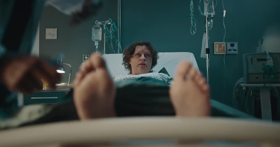 Doctor examines the feet of a hospitalized woman with a pen
