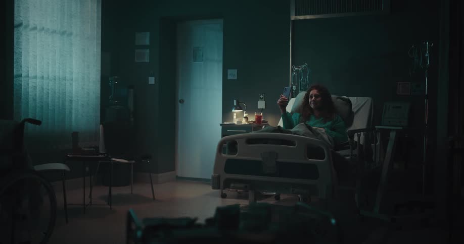 Woman in a hospital bed using her cellphone for a selfie