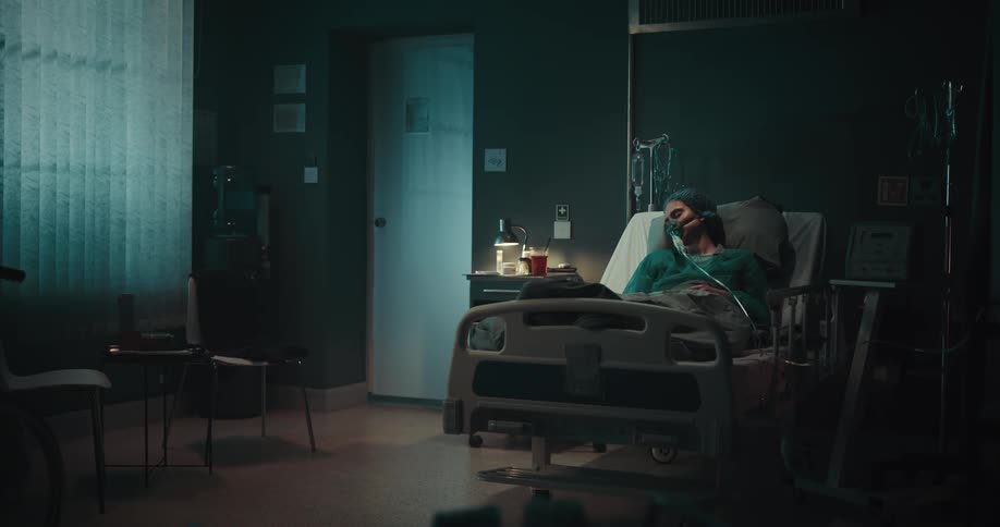 Woman lying on a hospital bed in a hospital room with medical devices sleeping