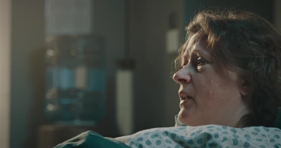 Sad female patient lies in hospital bed talks to the doctor