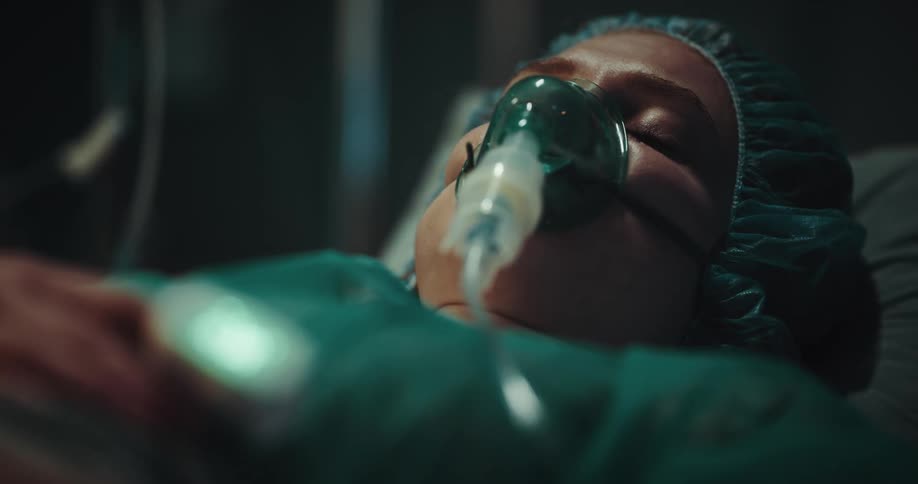 A person is lying in a hospital bed with an inhaler in their face