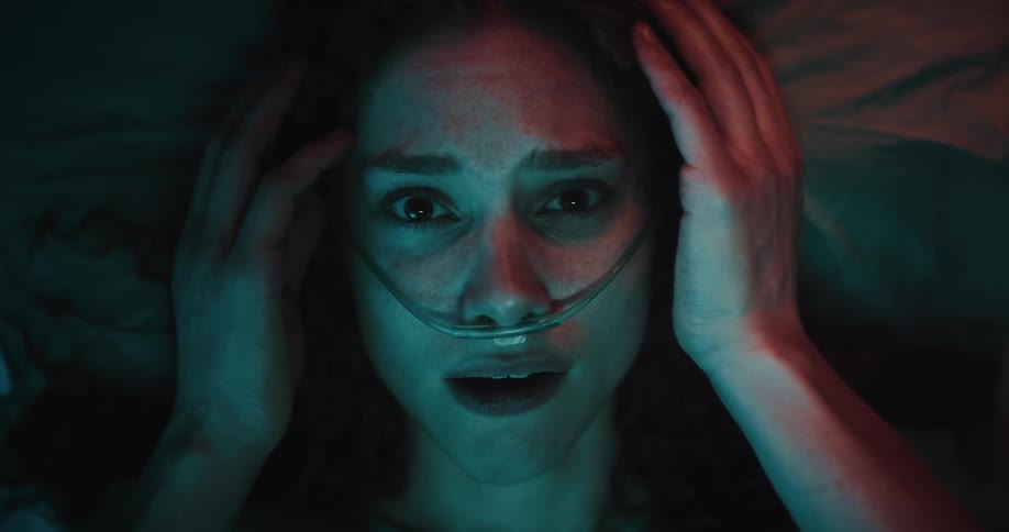 A woman with curly hair touches her nasal cannula in disbelief