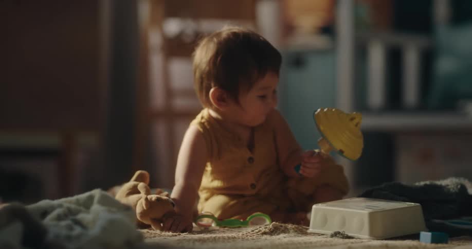 A toddler sits on the floor and plays with a group of toys