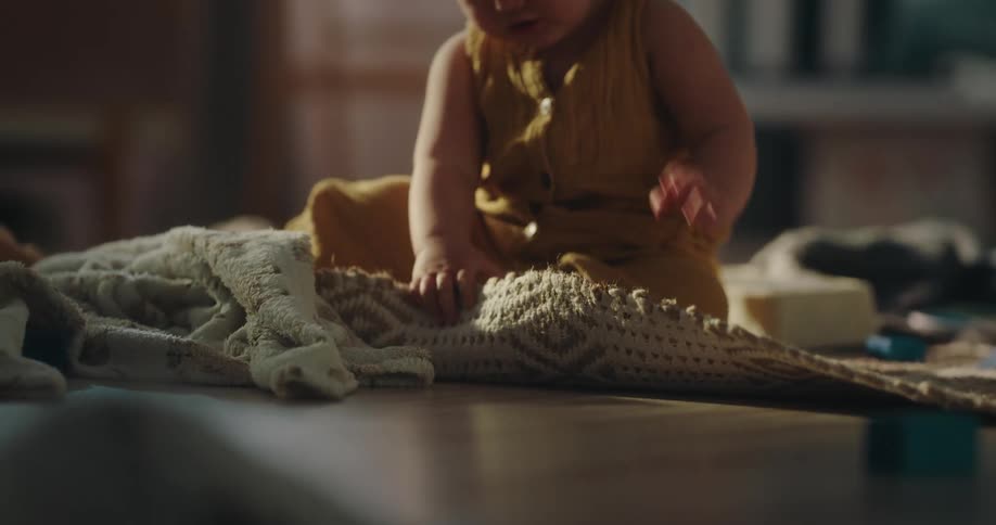 Asian baby sitting on the floor and pulling the rug upwards