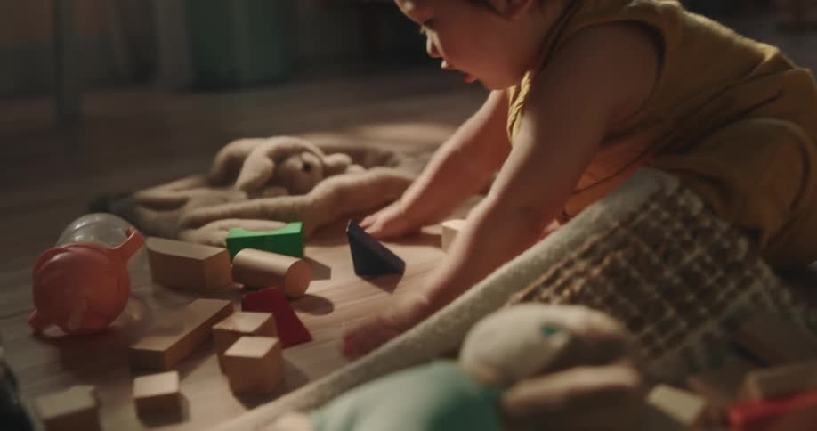 A baby is on the floor playing with many messy toys