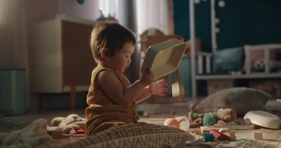 Young child plays on floor amongst scattered toys