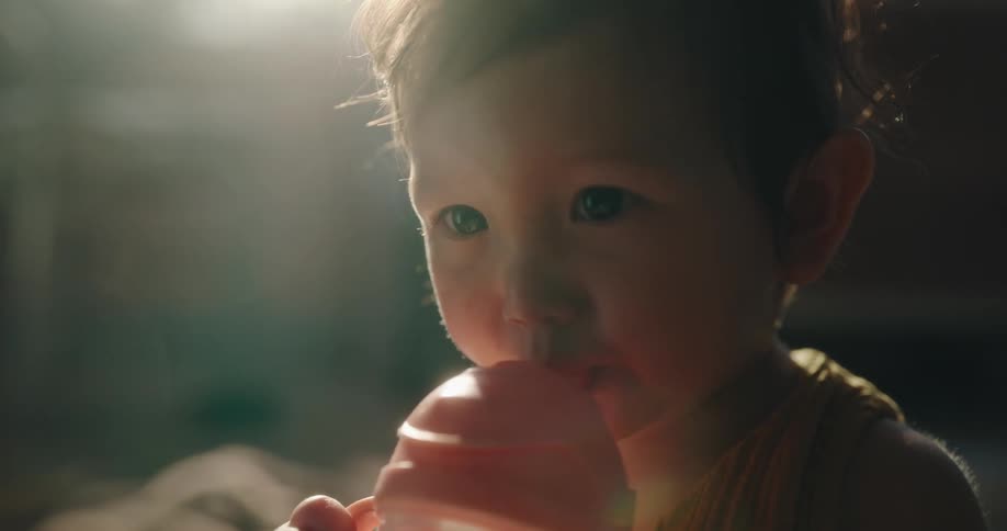 Baby girl sitting on the floor drinking water and then clapping her hands with joy