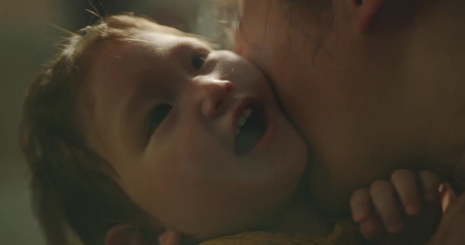 A mother holding her baby on her arms as she plays with him