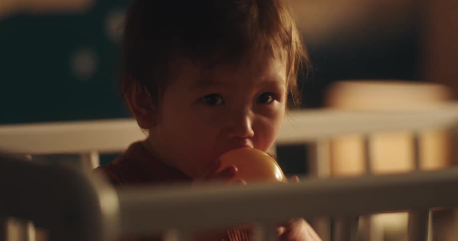 Closeup of a toddler playing with a ball in a crib
