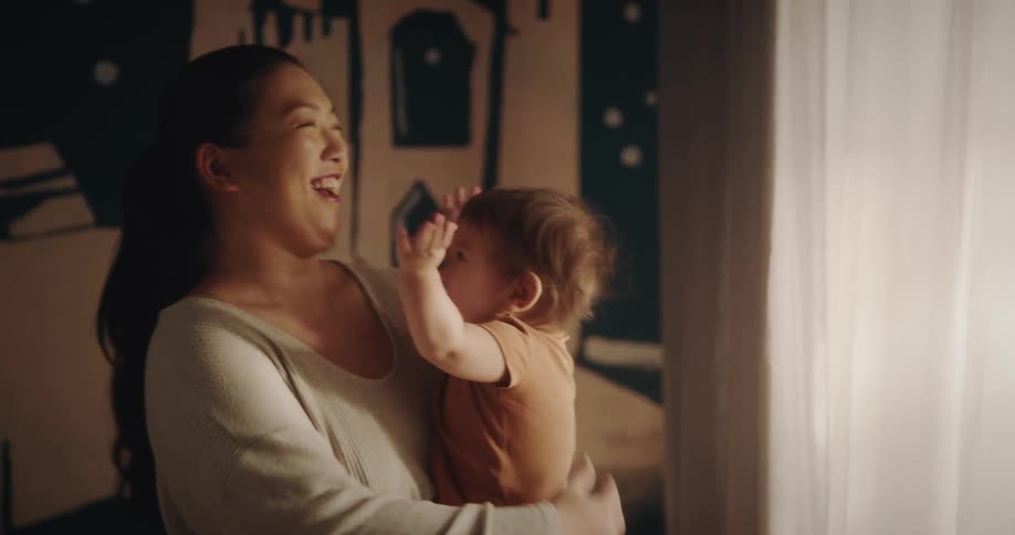 A baby on his mothers lap is happy and waving his arms