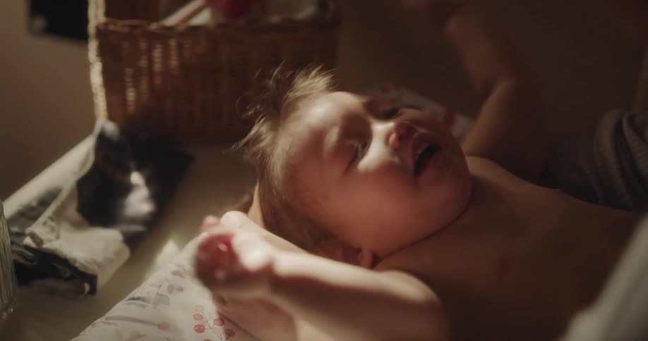 Mother changing the clothes of her happy baby who is clapping