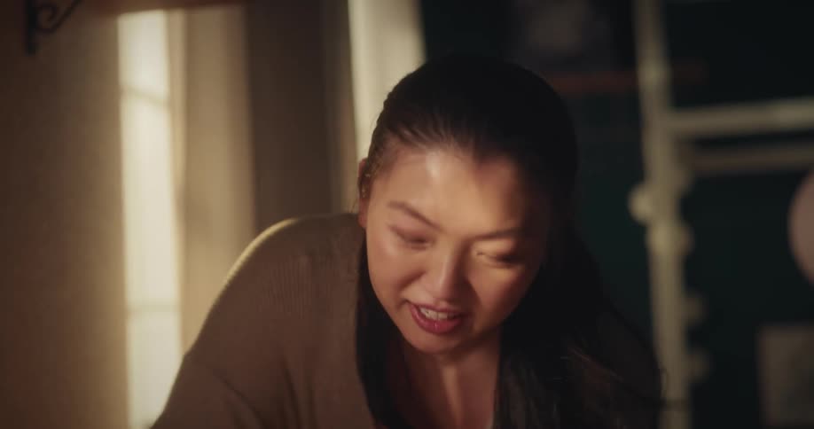 A mother looking at her baby who is lying down and making a happy face and kissing him on the belly
