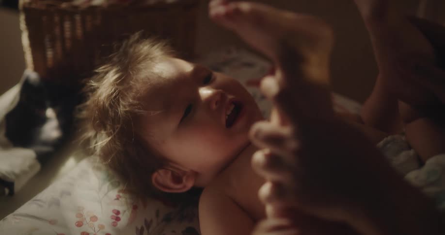 Hands of a person playing with a lying baby
