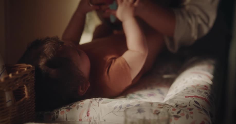 A mother changes her baby daughters diaper on a changing table