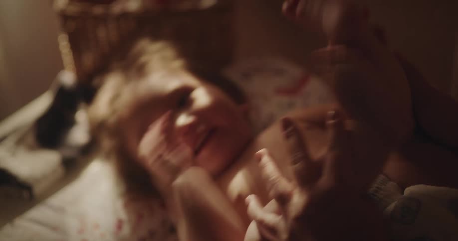 A woman playing with her baby lying on the bed